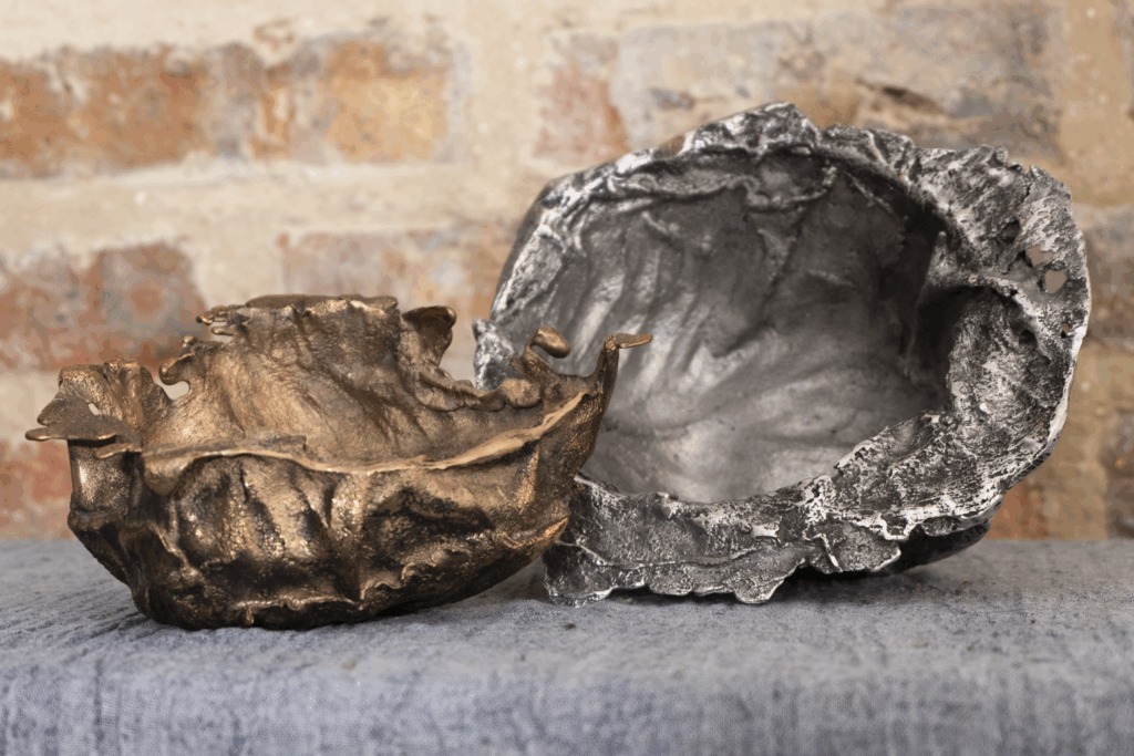 two bowls of cabbage leaves cast in metal, one bronze and one aluminum