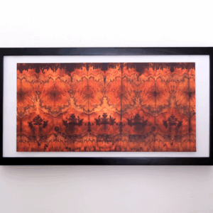 a chromatogram featuring bursts of red repeating acorss the print. It is hanging in a black frame.