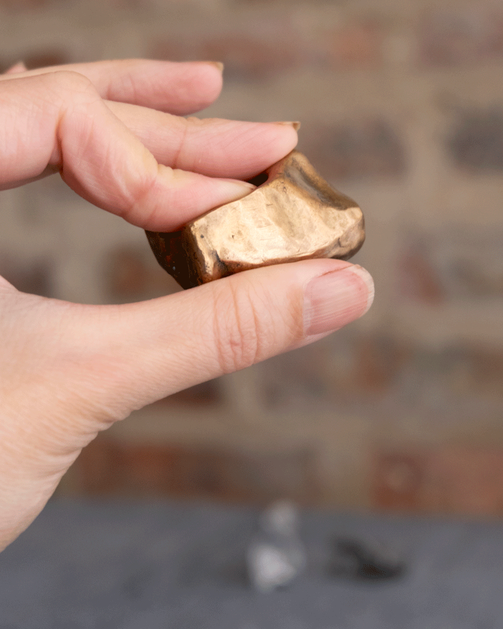 gif of light skinned fingers holding a bronze fidget toy in different positions